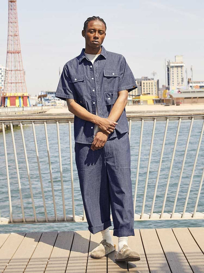 Alpha Industries Wide Leg Cotton Trouser, short-sleeve denim shirt, light socks, beige shoes.