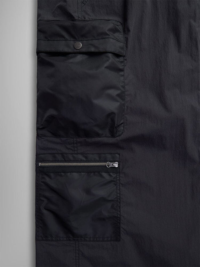 Close-up of the Women's M-65 Skirt by Alpha Industries, showcasing its black military-style design with two cargo pockets: one with a snap-button flap and the other with a zipper.