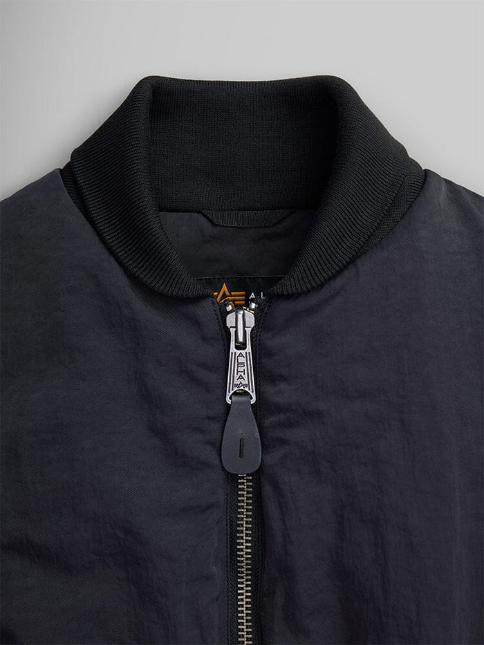 Close-up of the Women's Short Cinched Waist Jacket by Alpha Industries, showcasing its black design with a zipper closure and ribbed collar. The jacket features a quilted lining for added warmth.