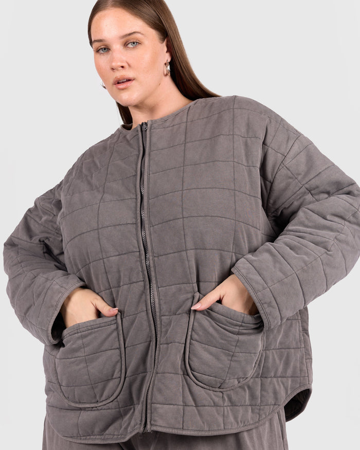 Woman wearing a gray quilted jacket on a white background